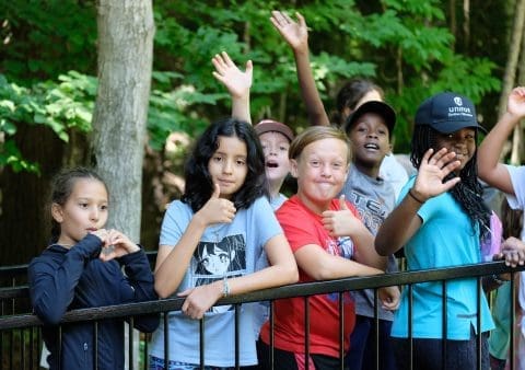 groupe d'enfant souriant derrière une clôture noir
